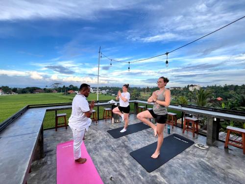 a group of people doing yoga on the deck of a house at Joni Ubud Hostel in Ubud