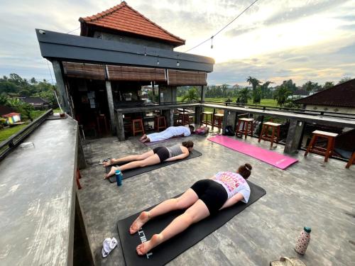 two women doing yoga on the roof of a building at Joni Ubud Hostel in Ubud