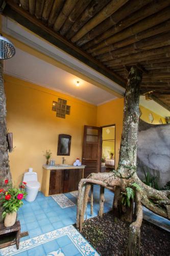 a bathroom with a tree in the middle of a room at DWan Tea Mountain Side in Jatiluwih