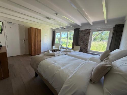 a large white bed in a room with a window at Hotel Ter Linde in Zuidwolde
