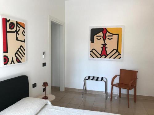 a bedroom with a bed and a chair and paintings at Corsica Rooms in Termoli