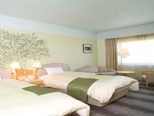 Rihga Royal Hotel Niihama tesisinde bir odada yatak veya yataklar