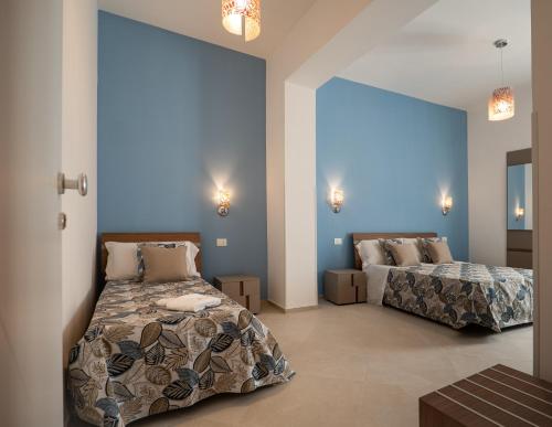 two beds in a room with blue walls at Monnalisa Rooms in San Vito lo Capo