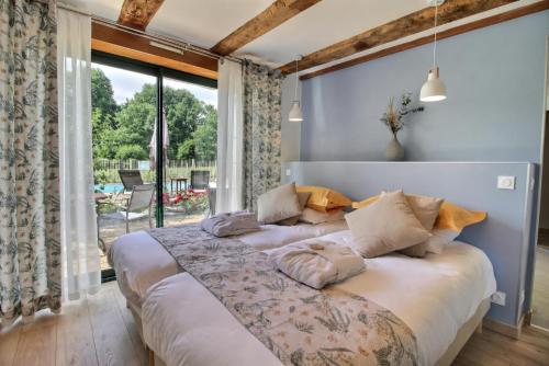 a bedroom with a large bed and a large window at La Lézardière in Pleugriffet