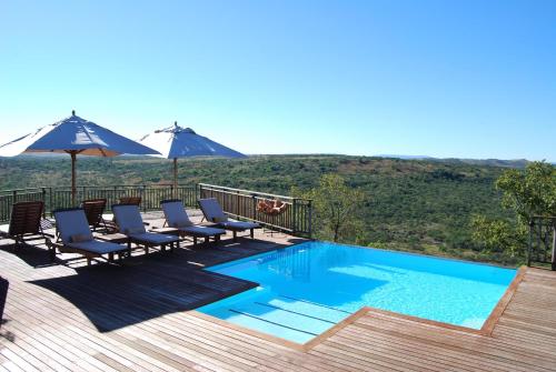 a swimming pool with chairs and umbrellas on a deck at Umzolozolo Private Safari Lodge & Spa in Nambiti Private Game Reserve