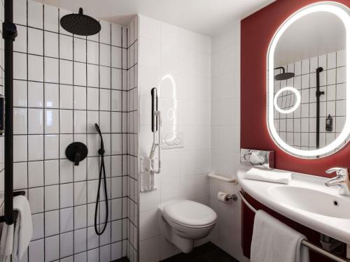 a bathroom with a toilet and a sink and a mirror at ibis Lausanne Centre in Lausanne