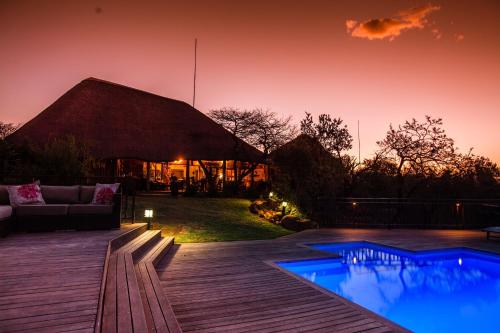 a house with a thatched roof with a swimming pool at Umzolozolo Private Safari Lodge & Spa in Nambiti Private Game Reserve