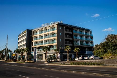 a building with cars parked in front of a street at Hotel Aroha in Seogwipo