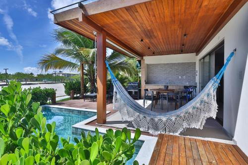 a hammock on the patio of a house with a swimming pool at Condominio Frente Mar 3 suites com Ar Cond piscina e Hidro privativa in Mata de Sao Joao