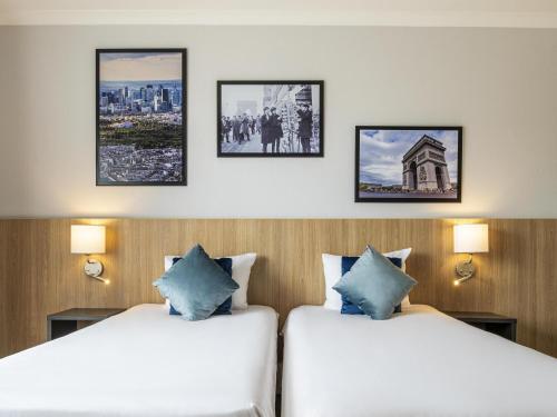 two beds in a hotel room with pictures on the wall at Aparthotel Adagio La Défense Kléber in Courbevoie