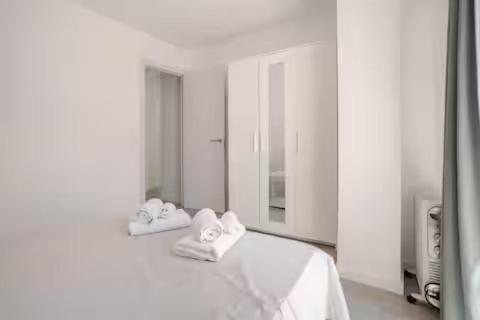 a white room with a bed with towels on it at Ático puerto Burriana in Burriana
