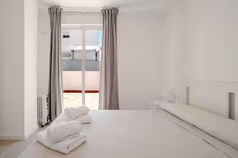 a white room with a bed and a mirror at Ático puerto Burriana in Burriana