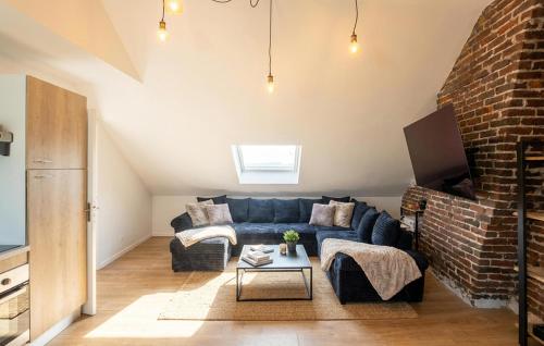 a living room with a blue couch and a brick wall at Appartement Proche Touquet in Étaples
