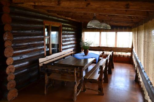 a dining room with a table and benches in a log cabin at Агроусадьба Кипшале in Vasyukovschina