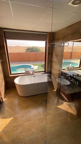 a large bathroom with a tub and a glass window at Desert Inn Resort and Camp in Ras al Khaimah