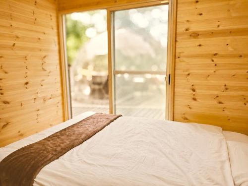 a bed in a wooden room with a window at イーリス軽井沢 in Naganohara