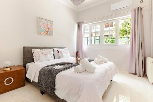 two beds in a bedroom with white walls and windows at Enora Loutraki Guesthouse in Loutraki