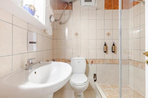 a bathroom with a tub and a toilet and a sink at Enora Loutraki Guesthouse in Loutraki