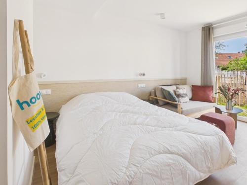 a bedroom with a white bed with a bag on the wall at Le Mid-Length- studio pour 3 - piscine commune in Biscarrosse