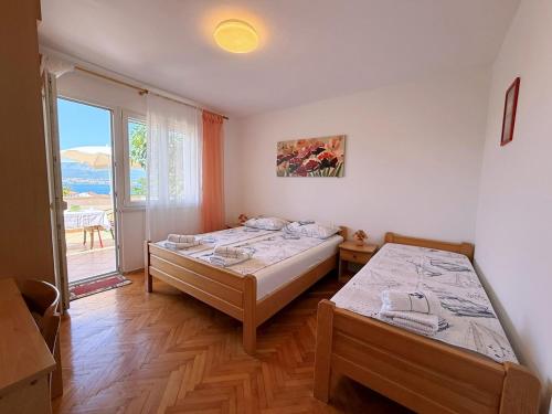 two beds in a room with a window at Apartments Dragica in Šilo