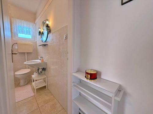 a white bathroom with a sink and a toilet at Apartments Dragica in Šilo