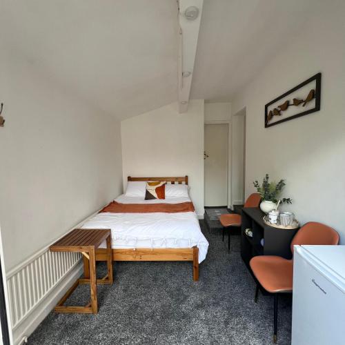 a bedroom with a bed and a desk and chairs at Rizvi house in Moston