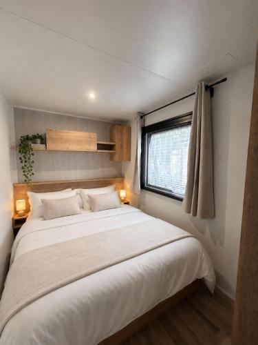 a large white bed in a room with a window at Escapade in Lège-Cap-Ferret