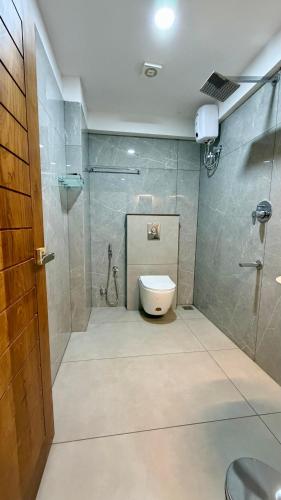 a bathroom with a shower and a toilet in it at TCS SUITES Chala Bypass Kannur in Thottada