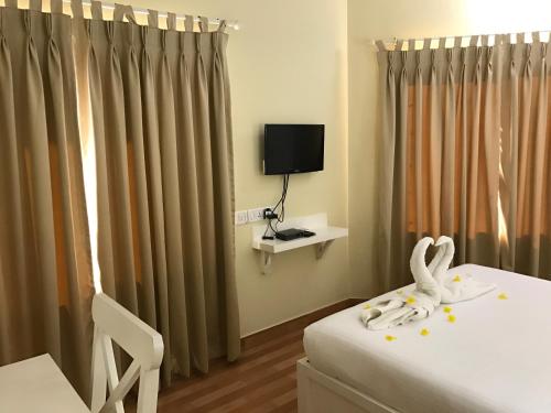 a room with a bed and a tv and curtains at Daffodils Spice Court in Cochin