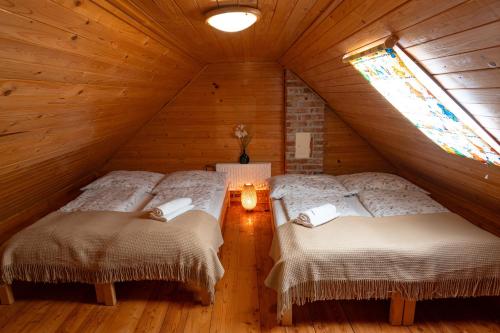 two beds in a attic room with a window at Sklípek Nechory in Prušánky