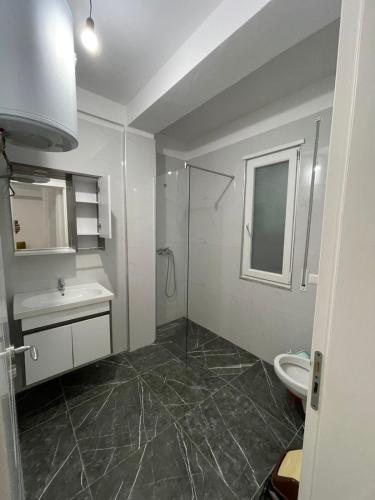 a bathroom with a shower and a sink and a toilet at Hotel Infinity Shëngjin in Lezhë