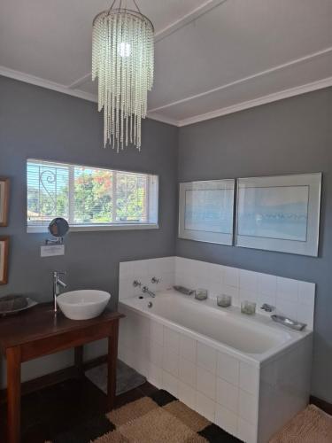 a bathroom with a tub and a sink and a chandelier at Burnham Road Suite Guest House in Bulawayo
