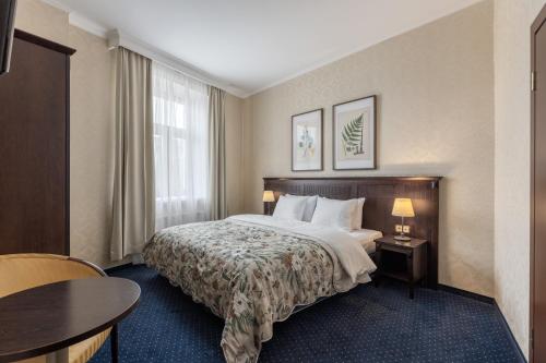 a hotel room with a bed and a table at Gertrude Hotel self check-in in Riga