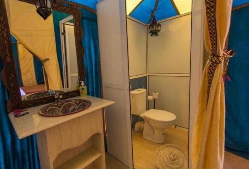 a bathroom with a toilet and a sink and a mirror at Palace desert camp in Merzouga