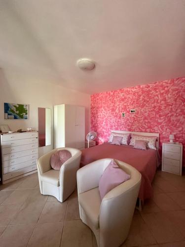 a pink bedroom with a bed and two chairs at Casa vacanze Alfano in Ascea