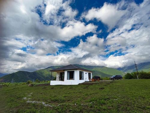 a small white house in a field with a car at Villa Tba near Borjomi, Tsemi and Sadgeri in Tsemi