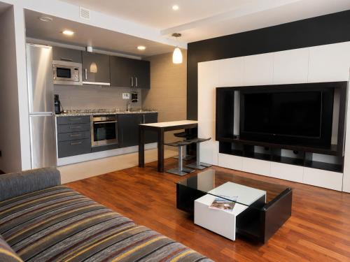 a living room with a couch and a flat screen tv at Hotel Apartamentos San Fermín Pamplona in Pamplona