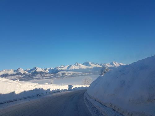 a road covered in snow with mountains in the background at Privát Tatry Štrba in Štrba