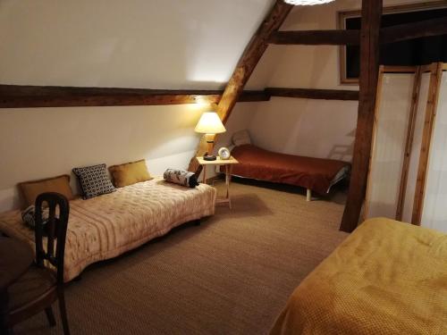 a bedroom with a bed and a couch in a room at Les Roses d Antan - 2 gîtes in Néville