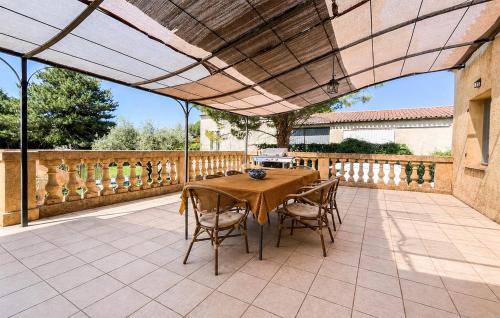 a patio with a table and chairs under awning at Maison Proche Uzès in Vers Pont du Gard