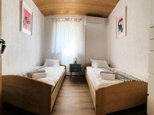 two beds in a room with a window at Villa Vika Apartments in Njivice