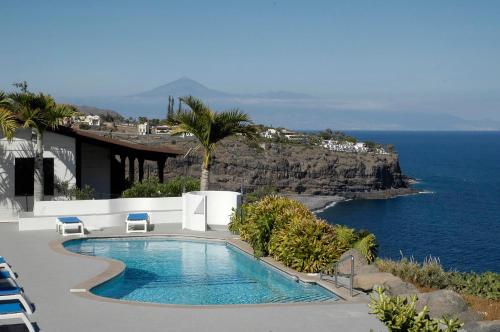 a swimming pool with chairs and a view of the ocean at Apartamentos Santa Ana - Adults Only in Playa de Santiago