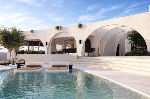 a swimming pool with two lounges in front of a house at Mamay Hotel in Fira
