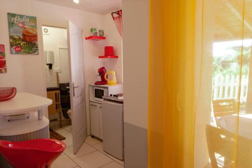 a kitchen with a red chair and a yellow curtain at Les Terrasses Levantines in Île du Levant