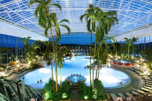 a large indoor pool with palm trees in a building at Kneipp-Kurhotel Steinle in Bad Wörishofen