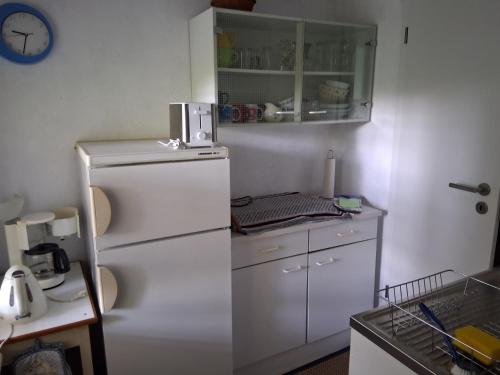 a kitchen with a white refrigerator and a clock on the wall at Bungalow im Künstlergarten in Bad Muskau