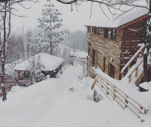 a house covered in snow with a bridge in the background at Zirve Dağ Evi in Kocaeli