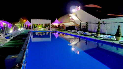 a swimming pool with tables and chairs at night at Juliana Platinum Brad in Brad