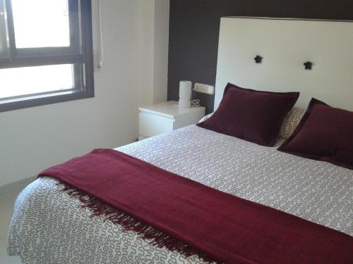 ベニカシムにあるAcogedor Apartamento en Benicasimのベッドルーム1室(紫のシーツが敷かれた大型ベッド1台、窓付)