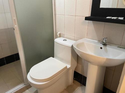 a bathroom with a white toilet and a sink at Hotel Benjamin Naval in Biliran